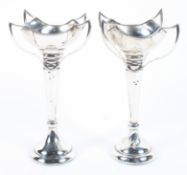 A pair of Edwardian arts and crafts silver vases, each with four flowing handles,