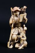 A 19th century Japanese ivory okimono of a wood cutter holding a book and staff accompanied by a