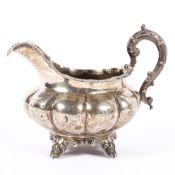 A Georgian silver sauce boat, the body of bulbous form with foliate decoration to its rim,