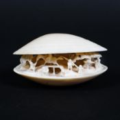 A Japanese 19th century ivory clam shell carved in openwork with a figure on horseback crossing a