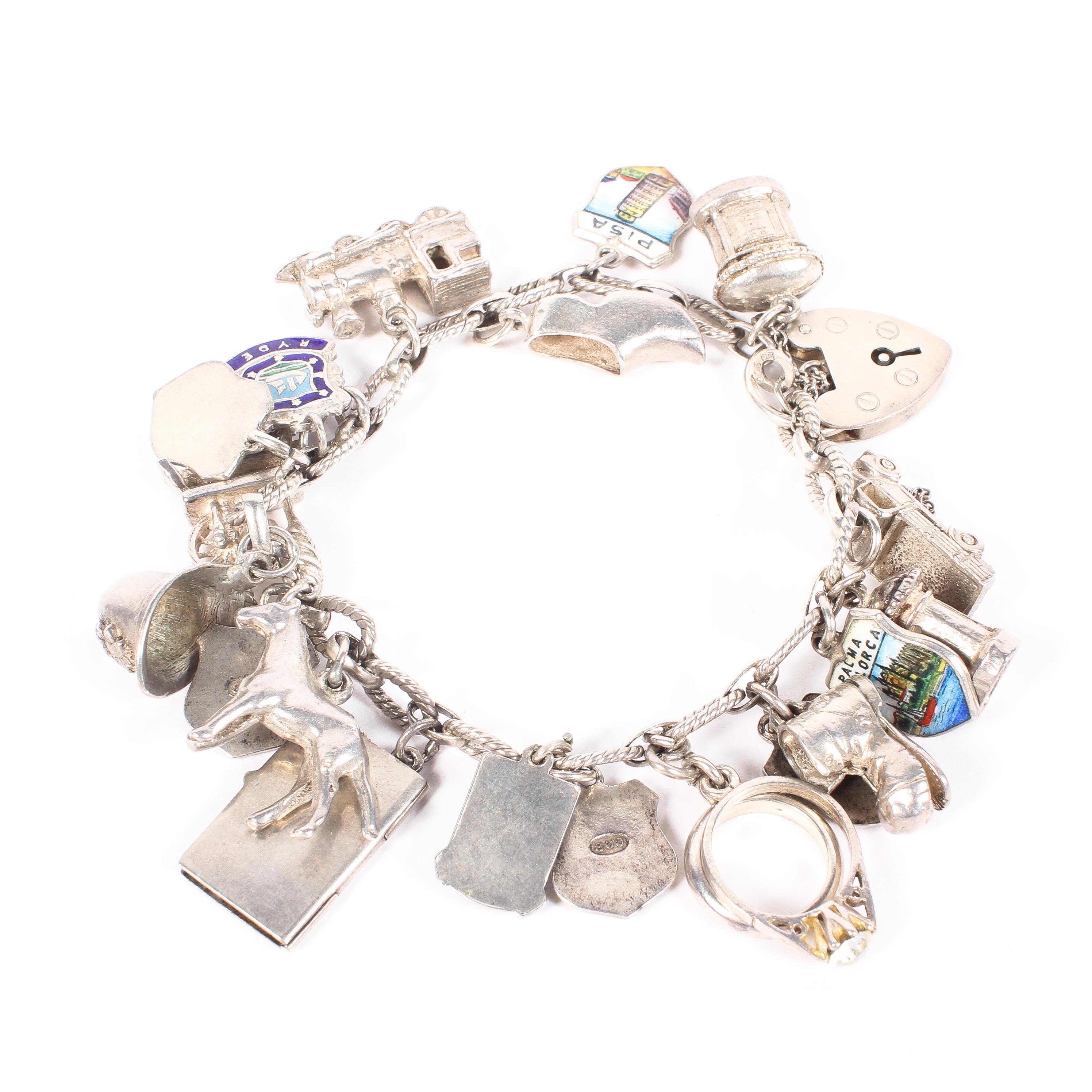 A sterling silver charm bracelet set with numerous silver and white metal charms. 47g.