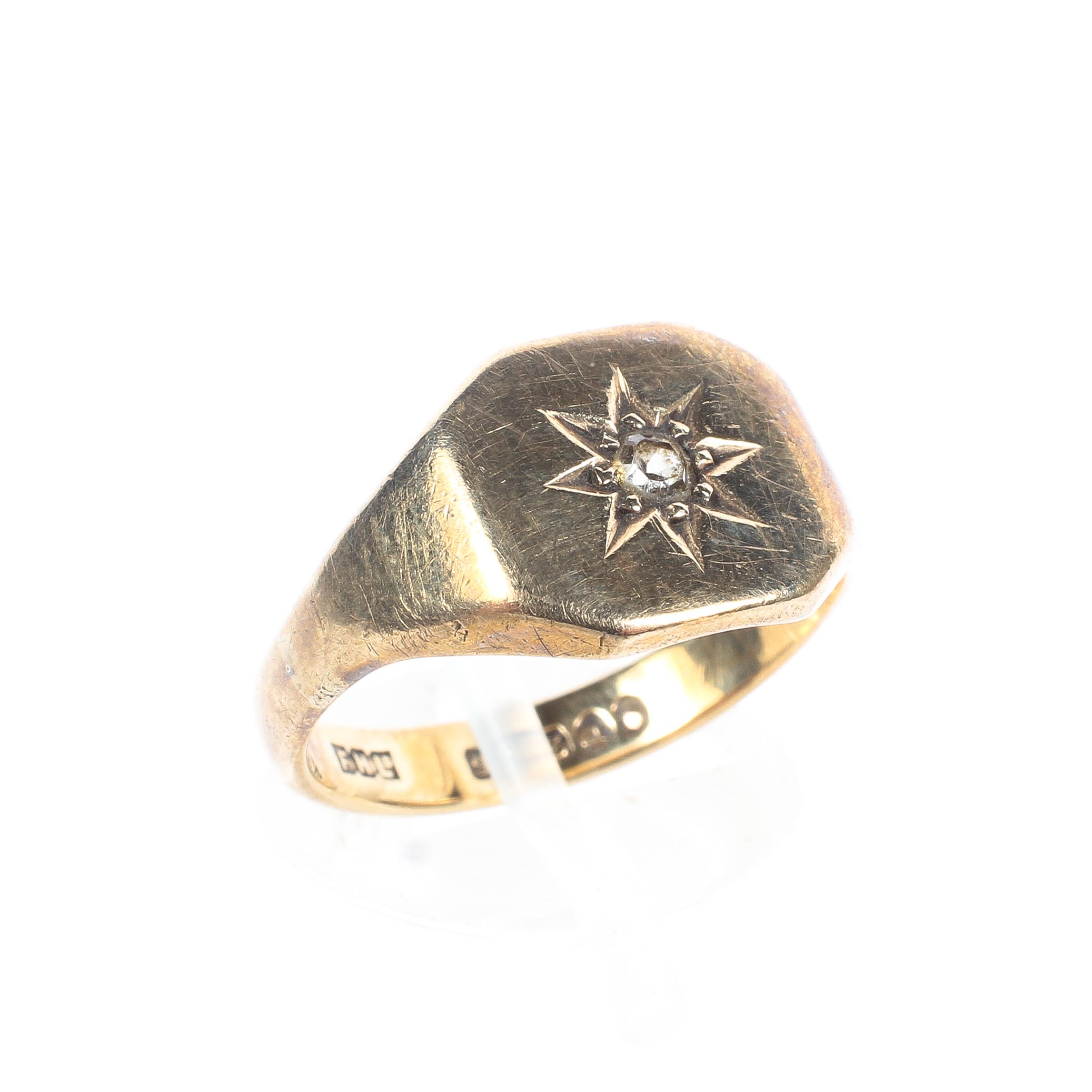 A 9ct yellow gold signet ring, set with a single white stone in a starburst mount to the centre, 3.