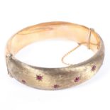 A 9ct gold bangle set with seven single cut rubies in star settings, 28.
