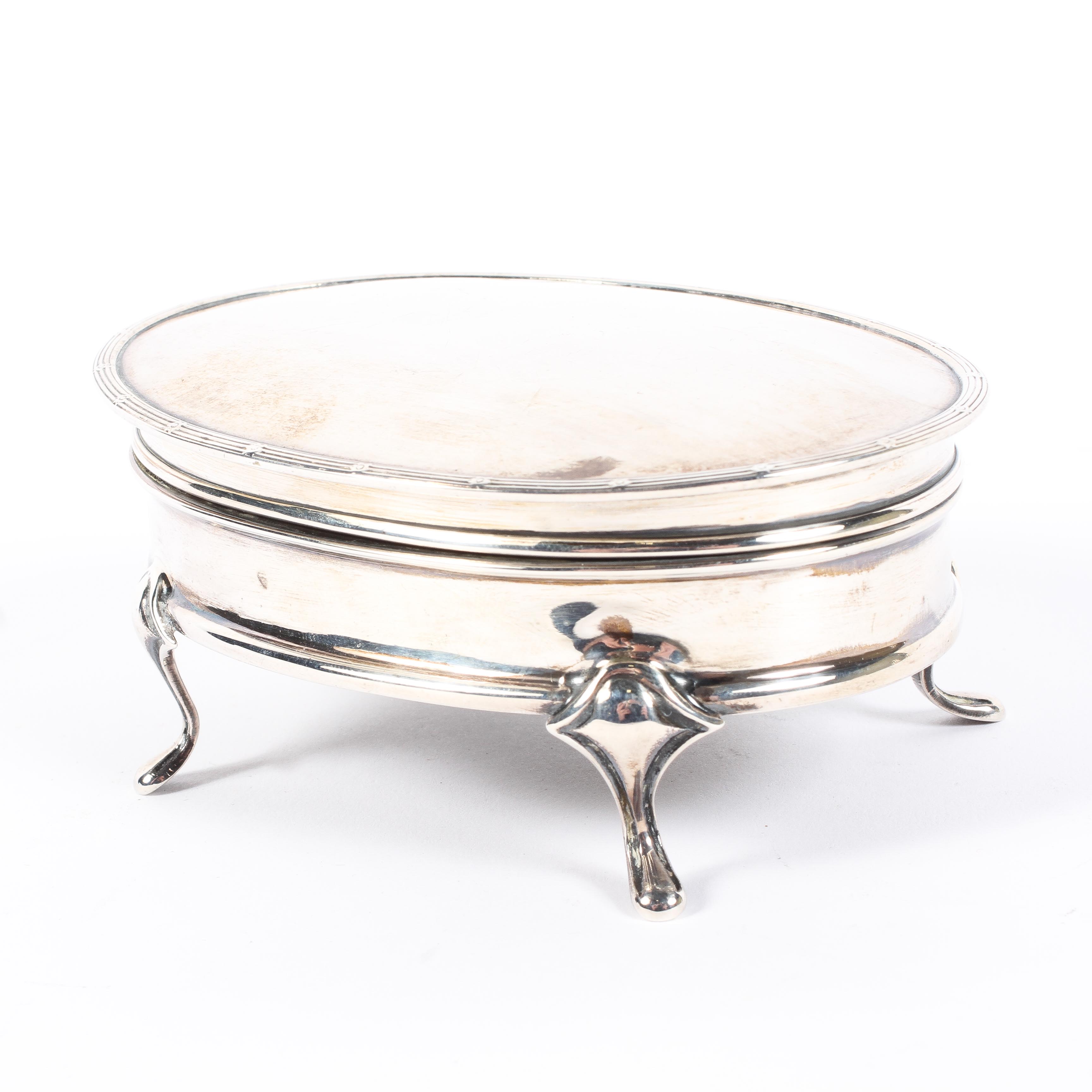 A George V silver trinket box, of oval form, the lid opening to reveal cushioned interior,