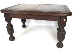 An early 20th century carved oak wind out dining table, raised on heavily carved baluster supports,