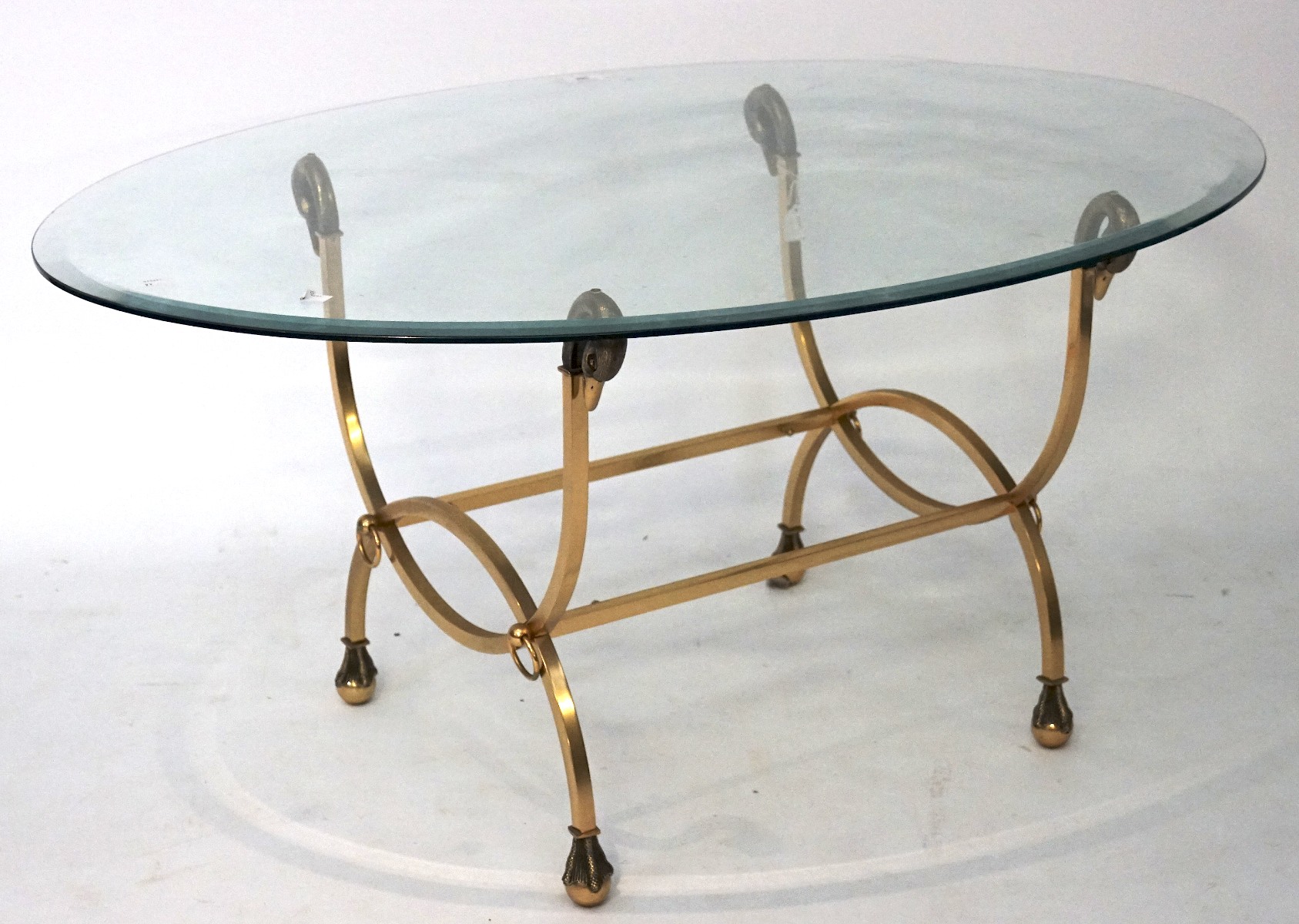 A contemporary bevelled edge glass topped table, of oval form,
