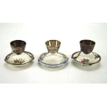 Three Christopher Dresser eggcups, each attached to a ceramic plate of assorted designs, height 6.