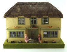 A 1930's doll's house, modelled as a cottage with a thatched roof,