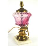 A 20th century oil lamp base, the brass structure with a pink glass reservoir,