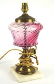 A 20th century oil lamp base, the brass structure with a pink glass reservoir,