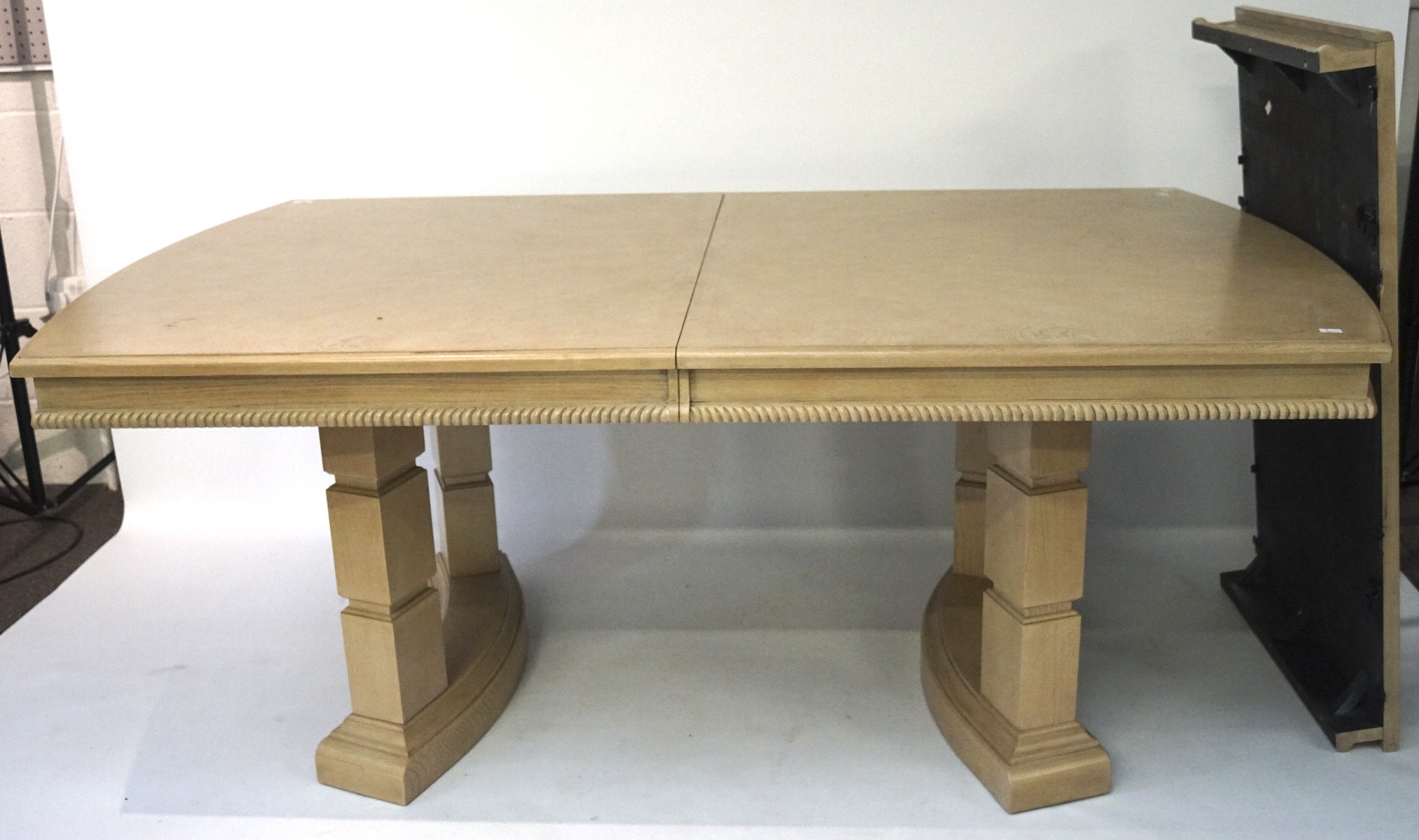 A large wooden extendable dining table, the wooden structure covered in grey veneer,