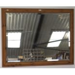 A large bevelled edge wall mirror, of rectangular form with a pine frame,