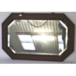 A 20th century oak bevelled edge wall mirror, of octagonal form with carved details to the frame,