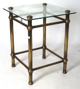 A contemporary glass topped side table, of square form, mounted on a brass frame,