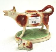 A Staffordshire creamer modelled as a cow, together with a miniature calf,