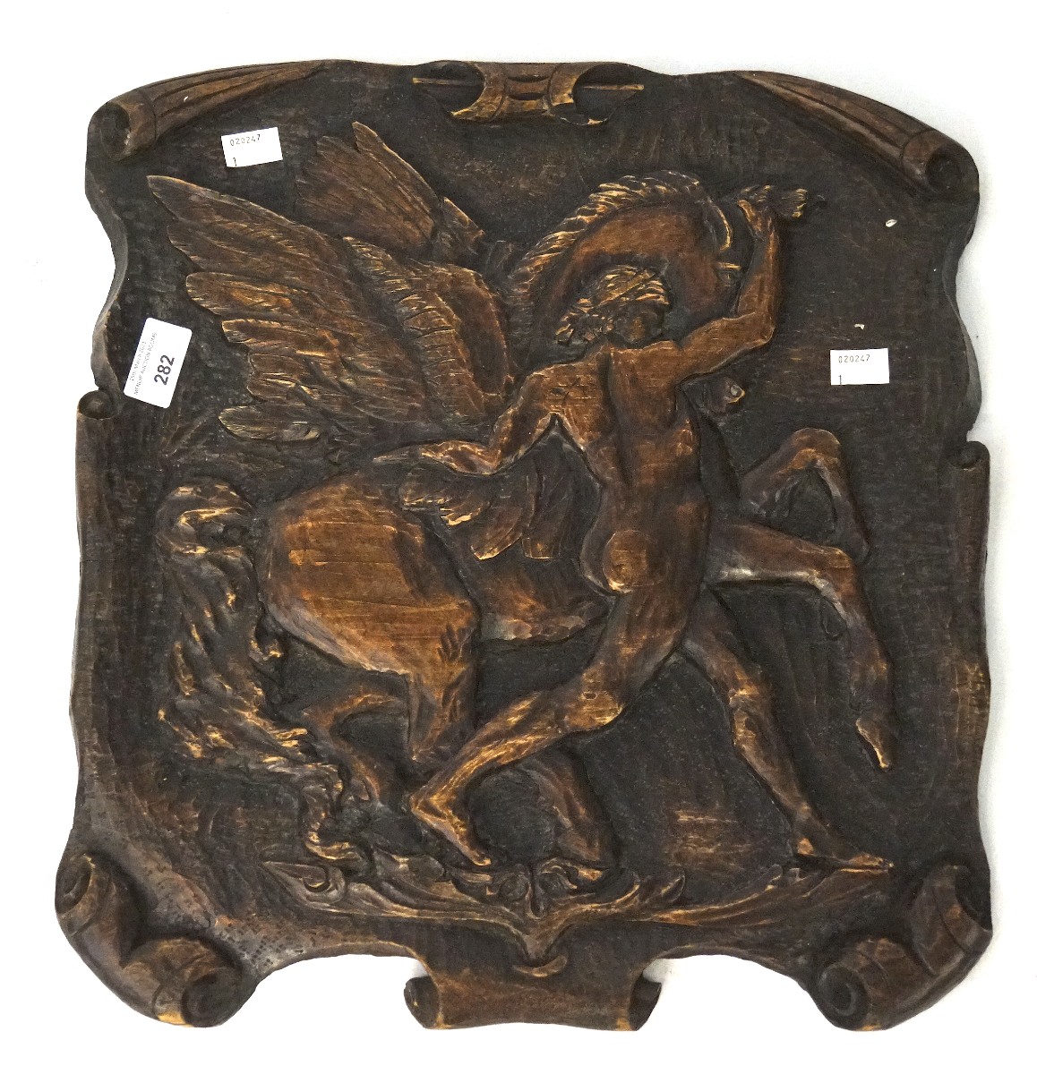A carved wooden plaque, featuring a nude figure alongside a horse,