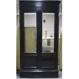 A large black lacquered wardrobe with glazed double doors, with moulded top and base, dismantled,