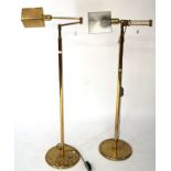 A pair of contemporary adjustable floor lamps, the cast brass frames mounted on circular bases,