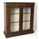 An early 20th century veneered display cabinet, with inlaid details and two glass panelled doors,