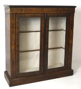 An early 20th century veneered display cabinet, with inlaid details and two glass panelled doors,