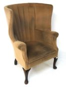 A large beige upholstered wingback armchair,