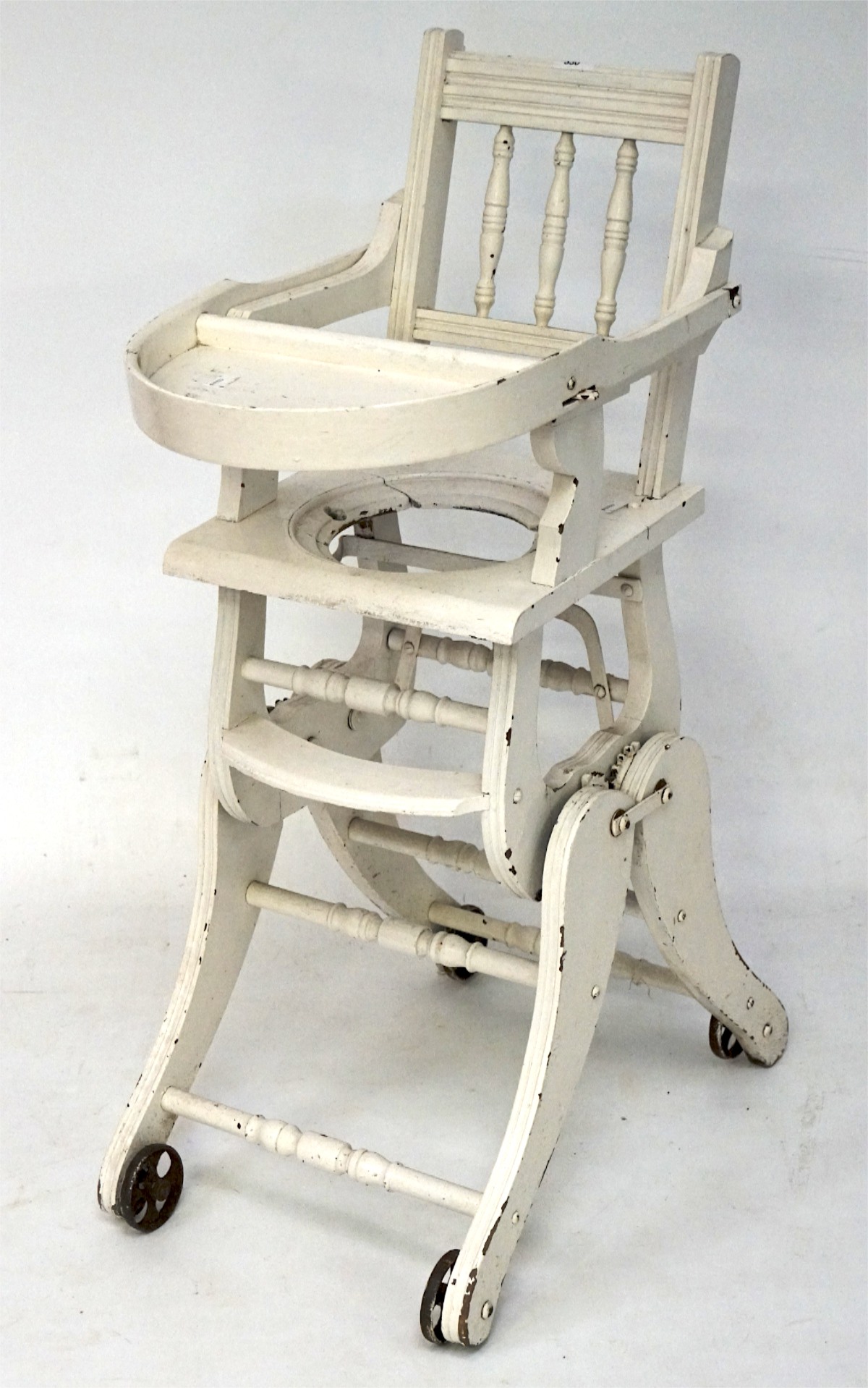 A vintage white painted metamorphic childs high chair, on four wheels,