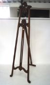 An early 20th century mahogany artist's easel with carved foliate elements,