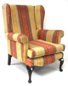 A contemporary large wingback armchair upholstered in mustard, red and green,