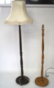 Two wooden standard lamps with turned supports on a round base, with one shade,