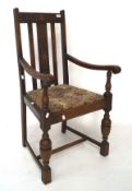 A early 20th century carver chair, the oak frame with carved details, raised on turned supports,