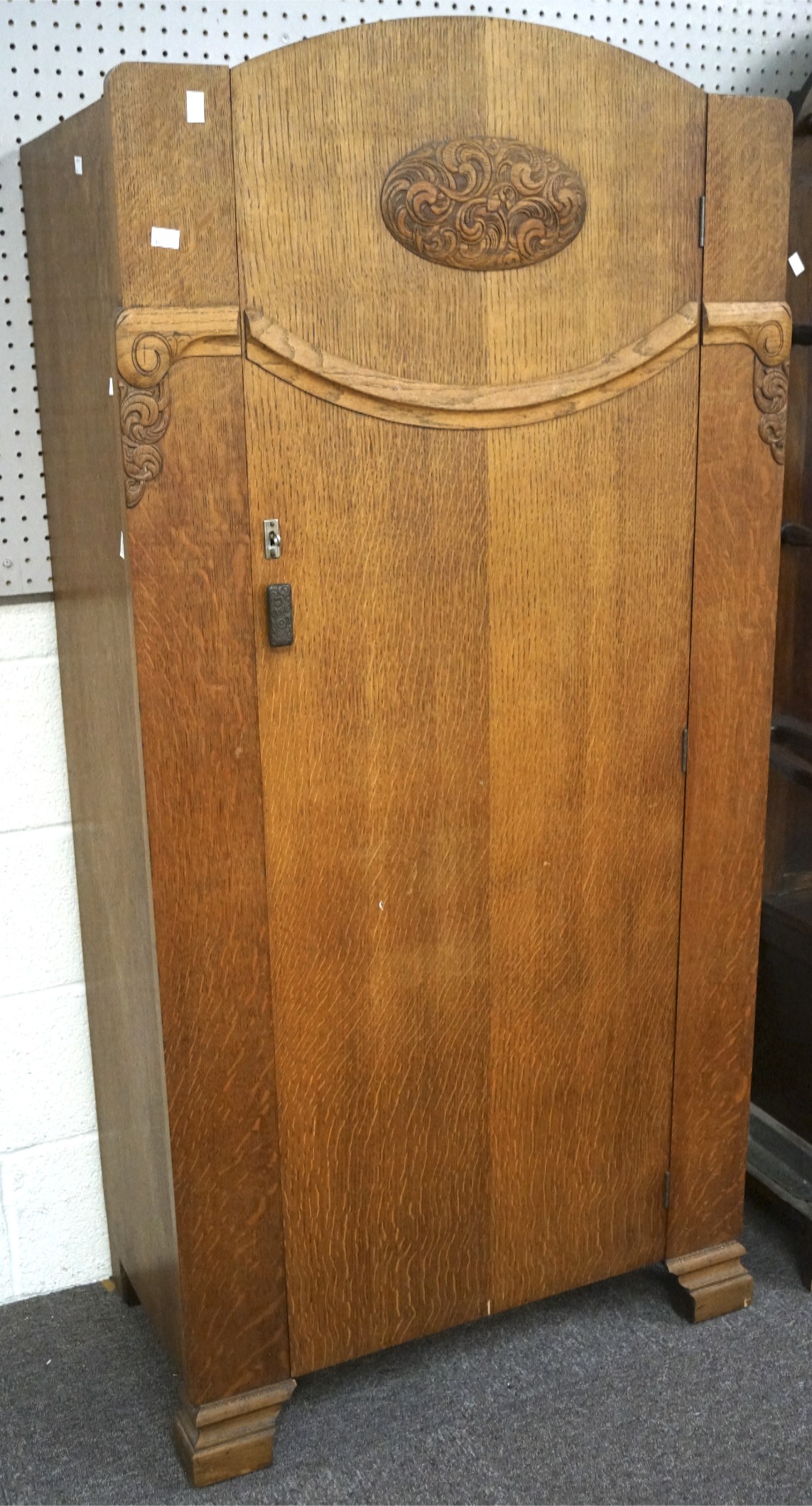 A mid century oak wardrobe, the front adorned with carved scrolling motifs,