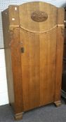 A mid century oak wardrobe, the front adorned with carved scrolling motifs,