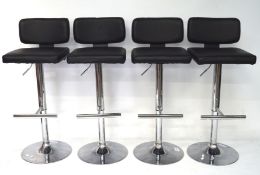 A set of four bar stools, with black upholstery on chrome stands,