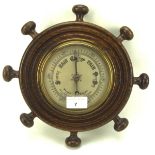 A 20th century barometer mounted in brass and oak in the shape of a ship's wheel,