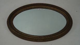 A large gilt framed bevelled edge wall mirror, of oval form,
