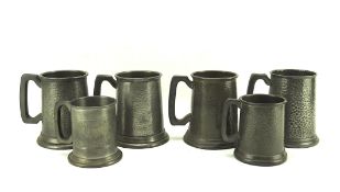 A colelction of six pewter mugs, two with glass bottoms, all with hammered decoration,