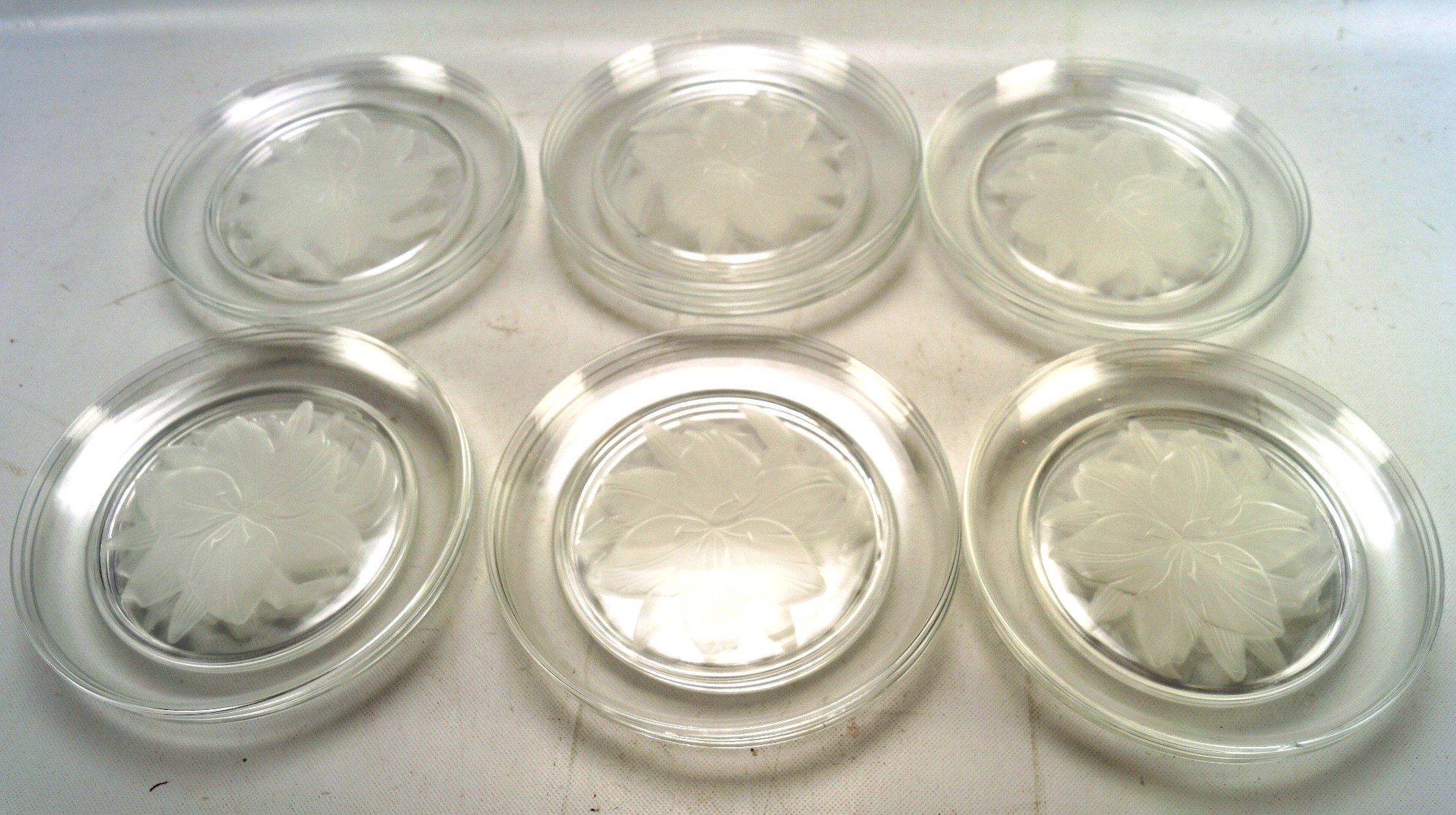 A set of crystal plates, all decorated with a floral image to the centre,