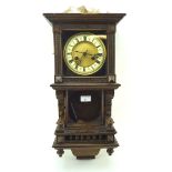 An early 20th century German wood cased wall clock, the face with Roman numerals denoting hours,