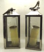 A pair of stainless steel candle lanterns, with carrying rope handles to the tops,