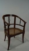 An early 20th century high backed wood armchair with wicker seat, on splayed front legs,