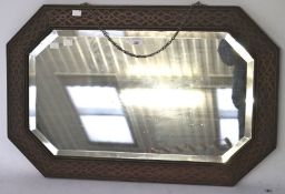 A 1930's oak bevelled edge wall mirror, of octagonal form with carved fretwork details to the frame,