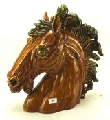 A large ceramic horses head with a green mane,