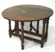 An oak gateleg oval table with bobbin turned supports, on bun feet,