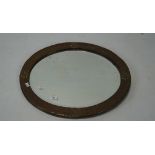 An arts and crafts copper mounted wall mirror, of oval form, adorned with floral motifs,