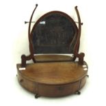 A 19th century oval swing mirror on a half moon three-drawer base, on metal ball and claw feet,