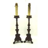 A pair of bronzed candlesticks on a tripod claw and ball foot, fitted for electricity,