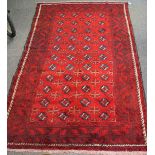 A Torkaman woven woollen carpet, the rug featuring a geometric pattern on a red ground,