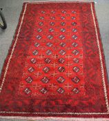 A Torkaman woven woollen carpet, the rug featuring a geometric pattern on a red ground,