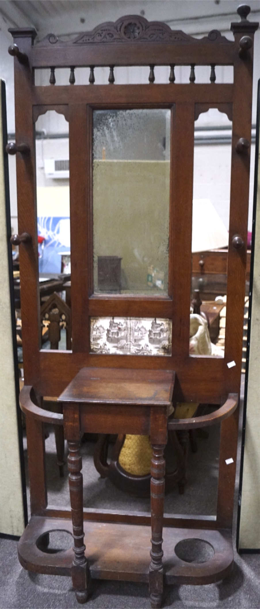 An Edwardian coat stick stand, with mirrored back and six coat pegs, above a central glove box,
