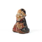 A small 18th/19th century painted wood netsuke of Okame seated with hands clasped,